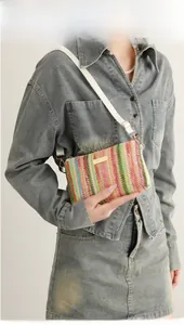 Détail du sac boîte tissé coloré avec plaque dorée et bandoulière blanche