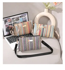 Vue détaillée des sacs bandoulière tressés avec perles et boucles dorées sur canapé