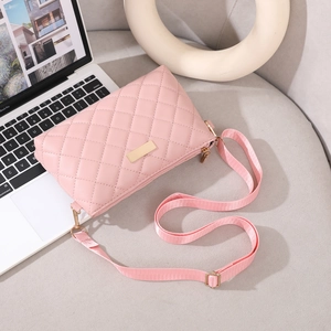 Close-up of pink quilted crossbody bag with gold metal plate on a white laptop