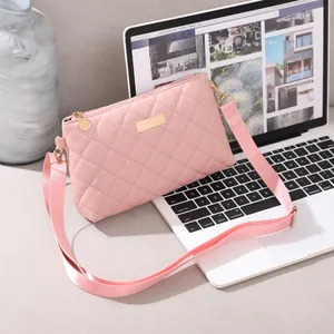 Pink quilted crossbody bag with gold metal plate detail resting on a laptop keyboard