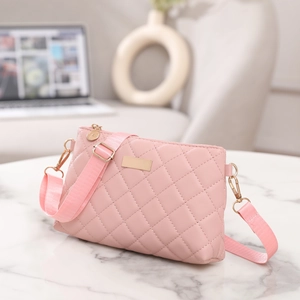 Detail of pink quilted PU leather bag with gold hardware on white marble surface