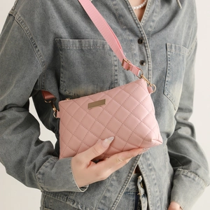 Detail of light pink quilted crossbody bag with gold hardware and wide nylon strap