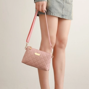 Close-up of pink quilted crossbody bag with golden plaque and adjustable strap