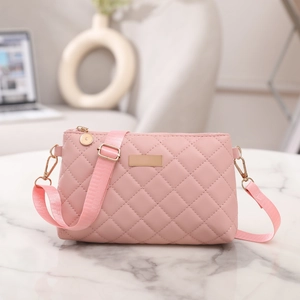 Detailed view of pink quilted handbag with gold hardware on white marble surface