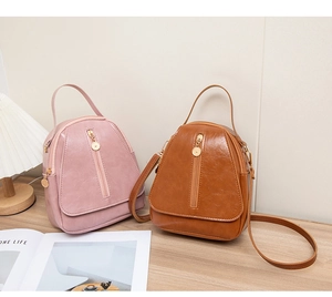 Detail of soft PU leather mini backpacks in pink and brown with golden zipper accents
