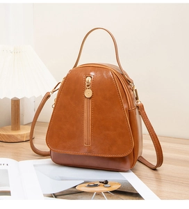 Caramel brown leather mini backpack with triangle flap and polished metal zipper detail