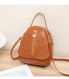 Detailed close-up of brown PU leather bag with vertical gold zipper on wooden table