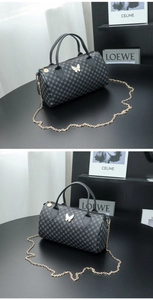 Detailed side view of a grey cylinder pillow bag with butterfly hardware and chain strap