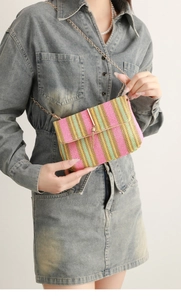 Detail of woven rainbow crossbody bag with gold chain strap and metal bar fringe tassel