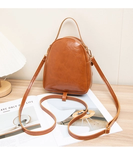 Brown vintage faux leather crossbody bag with multiple straps on a wooden table