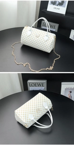 Detail of white cylinder bag with yellow geometric print and gold butterfly hardware