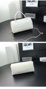 Detail of white cylinder bag with gold geometric patterns and metallic chain strap