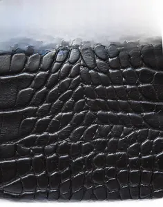 Detailed macro view of black crocodile pattern leather texture with matte finish on small handbag