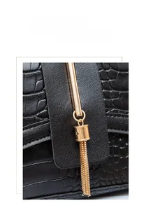 Detail of black crocodile texture handbag with decorative gold metal fringe and tassel