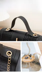 Detail of black crocodile texture bag with gold hardware and chain strap accents