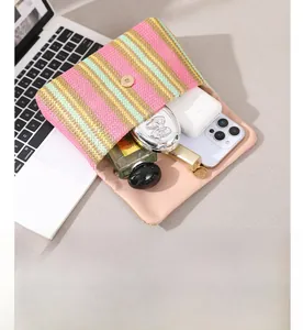 Rainbow woven straw clutch bag showing spacious interior with phone and cosmetics