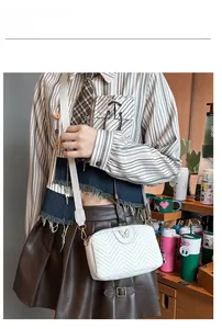 White crossbody camera bag with V-shaped quilting and gold butterfly logo on wide strap