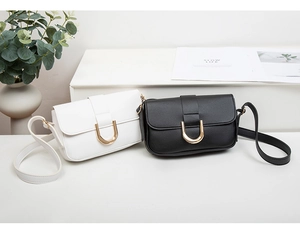 Primer plano de bolsos de hombro minimalistas en blanco y negro con hebillas doradas en U