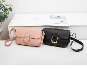 Detalle de bolsos bandolera rosas y negros con hebillas de metal dorado y textura de cuero