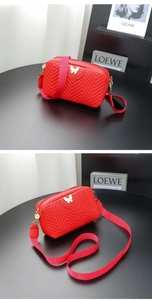 Detailed view of red quilted crossbody bag with gold butterfly charm and wide strap