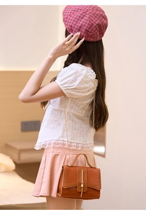 Detail of brown crocodile pattern small square bag with elegant golden chain strap