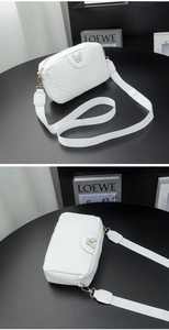 Detail of white quilted camera bag featuring golden butterfly clasp and wide shoulder strap