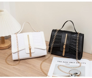 Detail of crocodile pattern handbags with metallic tassels and gold chain straps