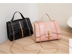 Detail of crocodile embossed leather bags in black and pink with gold tassels and chains