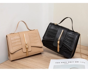 Detail of crocodile pattern handbags featuring metal tassels and gold chain straps