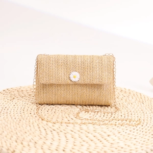 Straw crossbody bag with daisy flower and pearl accents on elegant gold chain strap
