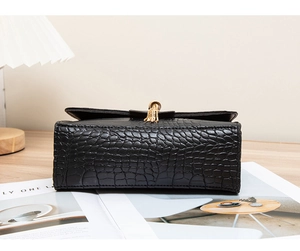 Close-up of black crocodile pattern leather handbag with gold tassel metal charm