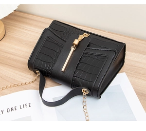 Detail of black crocodile texture bag featuring gold tassel and metal trim detail