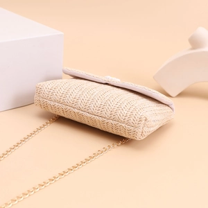 Detail of summer straw crossbody bag with pearl accents, daisy flower, and gold chain