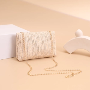 Detail of beige straw bag with herringbone weave, gold chain strap and daisy pearl decor