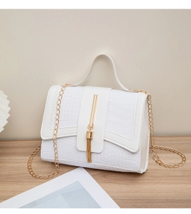 Close-up of white crocodile pattern shoulder bag with golden tassel buckle and chain strap