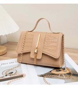Detail of khaki crocodile pattern handbag with gold fringe hardware and chain strap