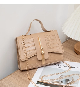 Detail of khaki crocodile pattern square bag with gold metal bar and fine fringe decoration