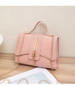 Detailed close-up of pink crocodile-pattern leather texture with gold tassel and chain