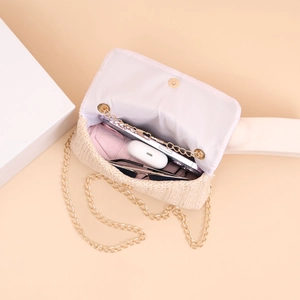 Detail of beige straw crossbody bag showing interior space with phone and sunglasses