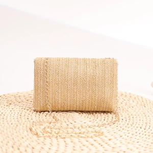 Detail of handwoven straw clutch with daisy accents and elegant gold metal chain