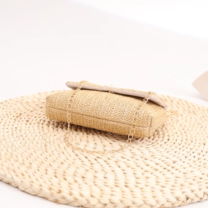 Close-up of woven straw bag with pearl floral accents and golden metal chain strap
