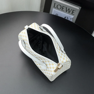 White Boston bag with golden geometric prints and dual handles on a black surface