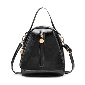 Glossy black trapezoid shoulder bag with gold hardware and vertical zipper on white background