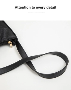 Macro shot of black lychee grain leather underarm bag with gold metal zipper detail