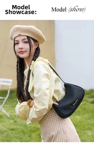 Close-up of black lychee grain leather crescent bag worn by a model in outdoor setting