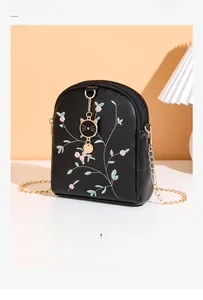 Détail de la broderie florale rose et du pendentif chat sur petit sac en cuir noir