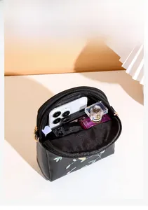 Détail du compartiment intérieur d'un petit sac bandoulière noir avec broderie florale