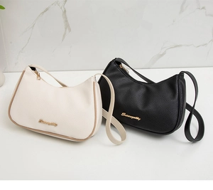 Detailed view of crescent underarm bags in lychee leather with golden metal logo accents