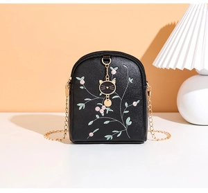 Détail du sac de téléphone en similicuir noir avec broderie florale et charm chat
