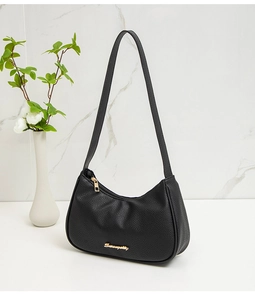 Detailed view of black lychee grain faux leather underarm bag with gold cursive logo
